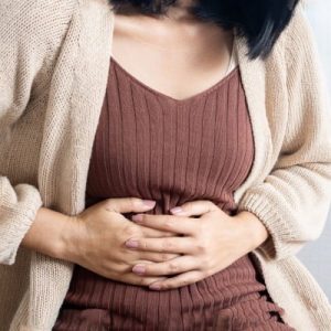 Natural Remedies for an Upset Stomach - woman standing and holding her stomach in pain